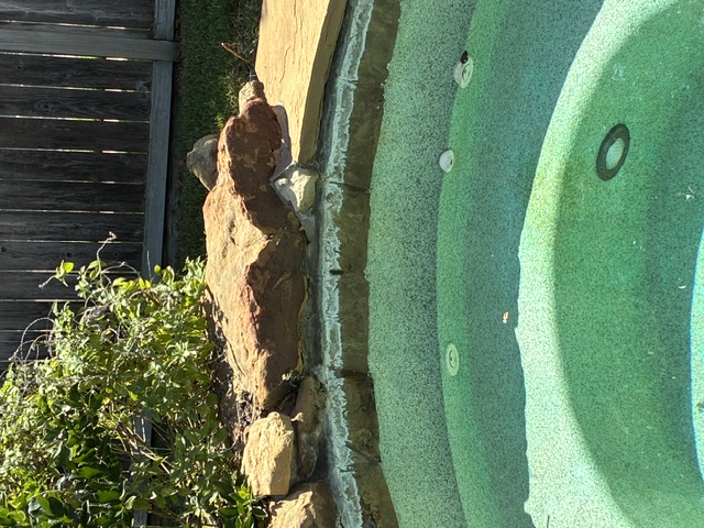 Before: Turquoise pool water meets a stone-faced edge beneath a wooden fence.